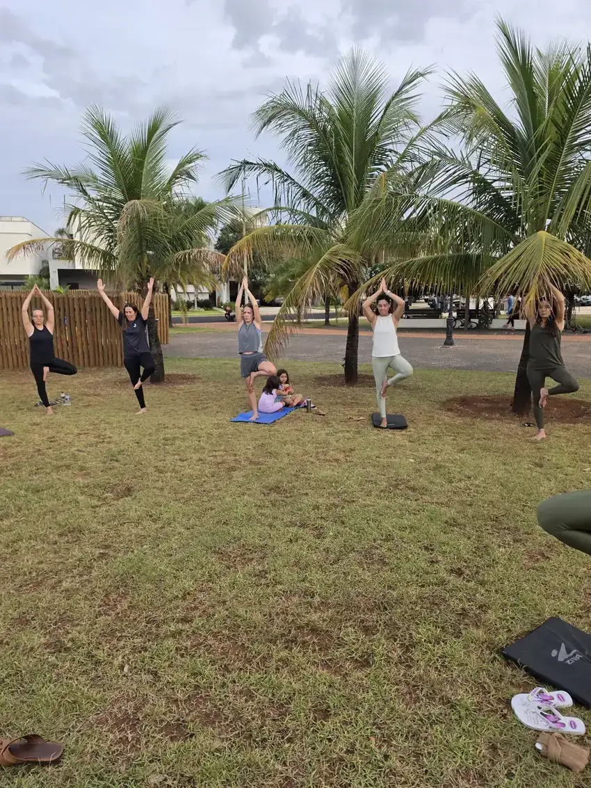 Grupo em postura da árvore em aula de yoga ao ar livre